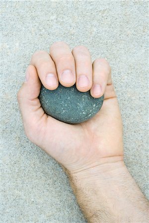 Man holding pebble in hand, cropped view Stock Photo - Premium Royalty-Free, Code: 696-03395414