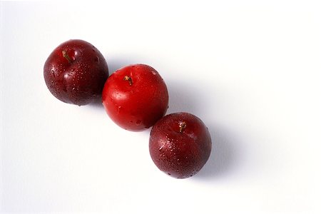 Three plums in a row, close-up Stock Photo - Premium Royalty-Free, Code: 696-03395518