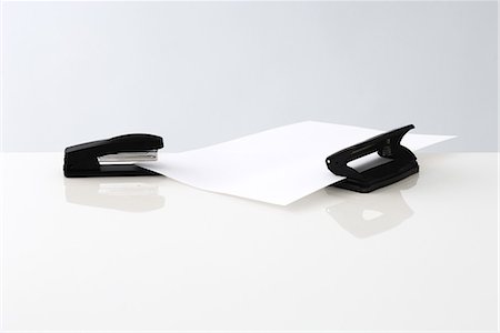 Stapler and hole puncher with single sheet of paper Foto de stock - Royalty Free Premium, Número: 696-03395871