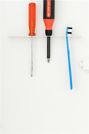 Toothbrush and screwdrivers hanging in toothbrush holder Stock Photo - Premium Royalty-Free, Code: 696-03395896