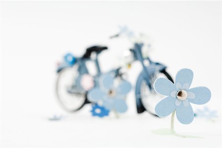 Craft flowers, toy bike in background Stock Photo - Premium Royalty-Free, Code: 696-03396087