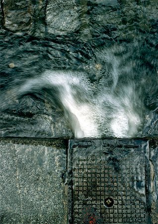 puddle road - Water pouring into gutter, high angle view, close-up Stock Photo - Premium Royalty-Free, Code: 696-03396894