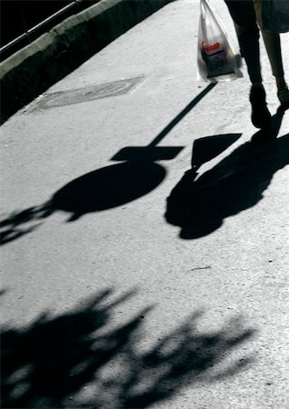 Person walking on street with bag, shadows. Stock Photo - Premium Royalty-Free, Code: 696-03397371