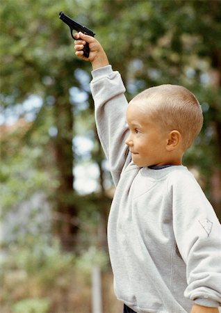 Boy holding toy gun, outside, rear view Stock Photo - Premium Royalty-Free, Code: 696-03398667