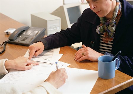 signing contract on computer - Two people sitting across from each other at table, looking at document Stock Photo - Premium Royalty-Free, Code: 696-03398871