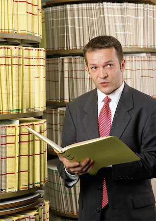 people filing records - Man holding file, shelves in background Stock Photo - Premium Royalty-Free, Code: 696-03398905