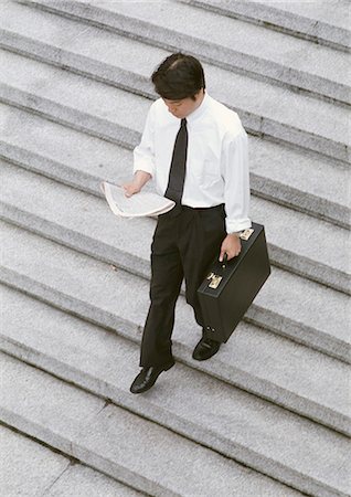 simsearch:695-03382908,k - Businessman reading newspaper while walking down steps, high angle view Fotografie stock - Premium Royalty-Free, Codice: 696-03399287