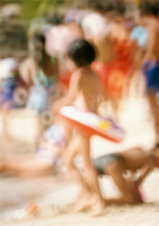 Fille portant un anneau en caoutchouc sur la plage, les gens en arrière-plan, floue Photographie de stock - Premium Libres de Droits, Code: 696-03399490