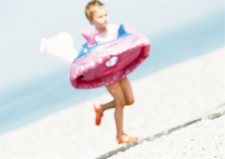 Child running with inner tube on beach, blurred Stock Photo - Premium Royalty-Free, Code: 696-03399597