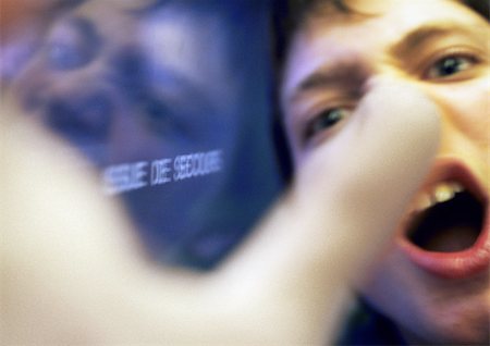 Teenage boy yelling, hand blurred in foreground, close up Foto de stock - Sin royalties Premium, Código: 696-03399645