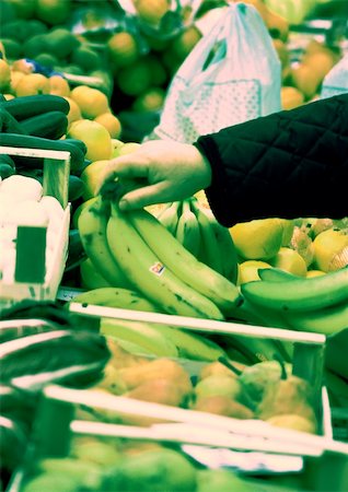 Hand choosing bananas from among produce, close-up Stock Photo - Premium Royalty-Free, Code: 696-03399928