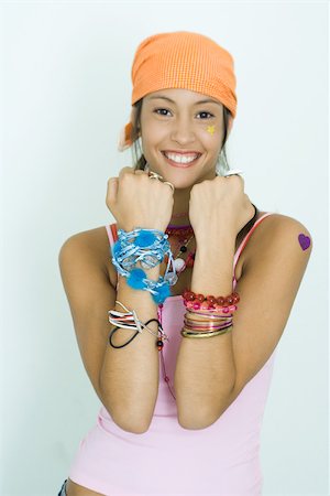 simsearch:695-05766837,k - Teen girl wearing lots of accessories, holding up forearms, smiling at camera, portrait Foto de stock - Sin royalties Premium, Código: 696-03393929