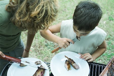 Two boys eating grilled meat Stock Photo - Premium Royalty-Free, Code: 696-03393920