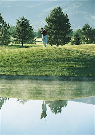 Golfer swinging near pond Stock Photo - Premium Royalty-Free, Code: 696-03400064