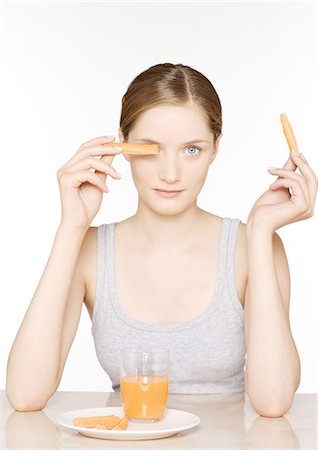 Jeune femme avec des bâtonnets de carottes et de jus de carotte Photographie de stock - Premium Libres de Droits, Code: 696-03400149