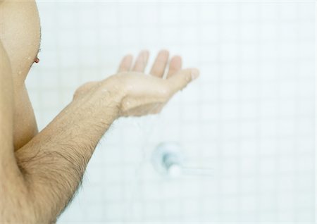 Man holding out hand in shower Stock Photo - Premium Royalty-Free, Code: 696-03400426