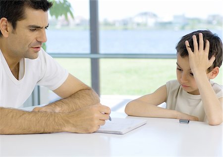 Boy doing homework with father's help, cropped Stock Photo - Premium Royalty-Free, Code: 696-03400481