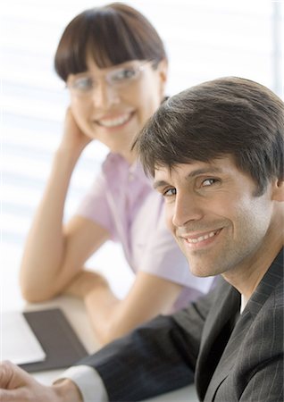 simsearch:632-01155400,k - Businessman smiling, female colleague in background Stock Photo - Premium Royalty-Free, Code: 696-03400507