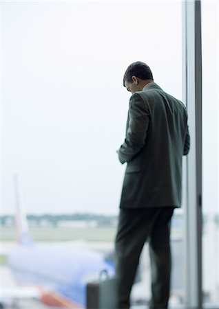 Man standing looking down, airplane in background Stock Photo - Premium Royalty-Free, Code: 696-03400609