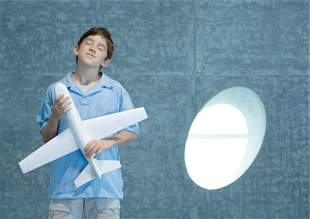 Boy holding toy airplane, closing eyes Stock Photo - Premium Royalty-Free, Code: 696-03400764