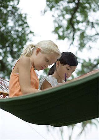 simsearch:632-03193191,k - Two girls sitting in hammock, writing Foto de stock - Royalty Free Premium, Número: 696-03400819