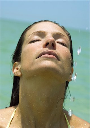 simsearch:632-01146602,k - Woman with head back and drops of water in the air, sea in background Stock Photo - Premium Royalty-Free, Code: 696-03400901