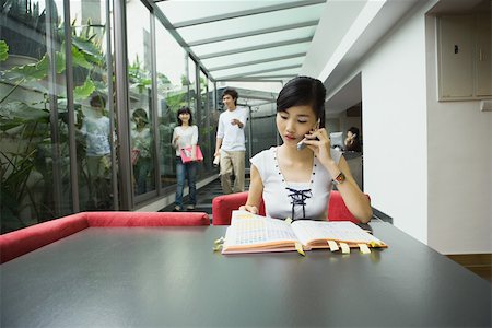 students campus phones - Young woman sitting at table using cell phone Stock Photo - Premium Royalty-Free, Code: 696-03401140