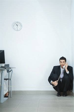 exclusion business - Businessman sitting on floor, in corner, talking on phone Stock Photo - Premium Royalty-Free, Code: 696-03401163