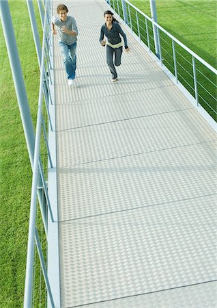 friends race - Teenage couple running on walkway, high angle view Stock Photo - Premium Royalty-Free, Code: 696-03401196