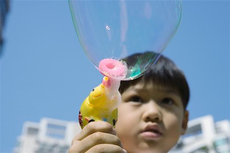 Boy making bubbles with bubble wand Stock Photo - Premium Royalty-Free, Code: 696-03401220