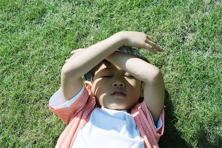 simsearch:695-03378158,k - Boy lying on grass, holding arms over face Fotografie stock - Premium Royalty-Free, Codice: 696-03401221