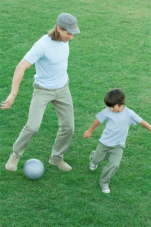 dad playing soccer with kids - Man and boy playing soccer on grass Stock Photo - Premium Royalty-Free, Code: 696-03401398