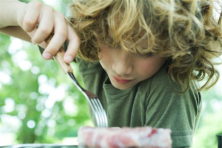 simsearch:696-03401434,k - Boy picking up piece of raw meat with fork Stock Photo - Premium Royalty-Free, Code: 696-03401448