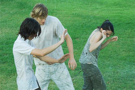 Group of young friends standing in water spray, getting wet Stock Photo - Premium Royalty-Free, Code: 696-03401498