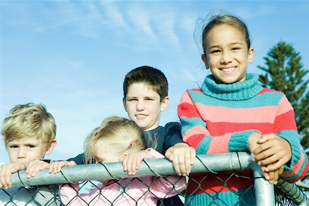 simsearch:695-03373539,k - Children standing behind wire fence, smiling at camera Stock Photo - Premium Royalty-Free, Code: 696-03401539
