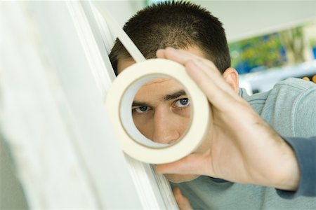 simsearch:695-03389240,k - Man putting masking tape on surface, looking through hole Stock Photo - Premium Royalty-Free, Code: 696-03401593