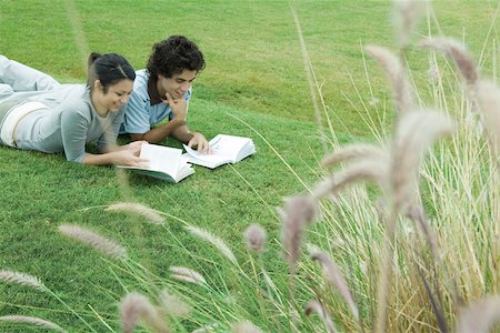 simsearch:632-05400916,k - Young adult couple reading outdoors, lying on grass Foto de stock - Royalty Free Premium, Número: 696-03401616