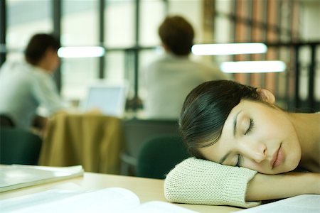 Female college student sitting at table in library, resting head on table Stock Photo - Premium Royalty-Free, Code: 696-03401658