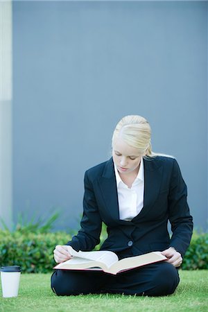 simsearch:632-01148045,k - Businesswoman sitting on grass reading book, coffee cup nearby Stock Photo - Premium Royalty-Free, Code: 696-03401757