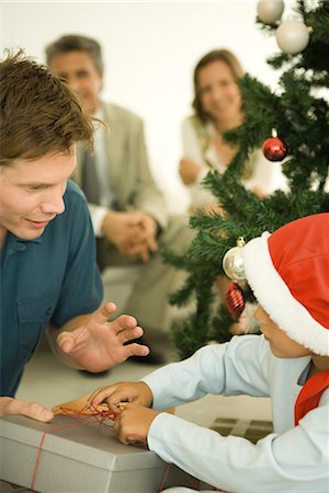 simsearch:696-03394247,k - Père et fils ouverture Noël présentent devant l'arbre de Noël, garçon coiffé de Santa Photographie de stock - Premium Libres de Droits, Code: 696-03401866