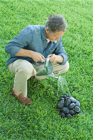 Man watering pile of stones, full length, high angle view Stock Photo - Premium Royalty-Free, Code: 696-03401947