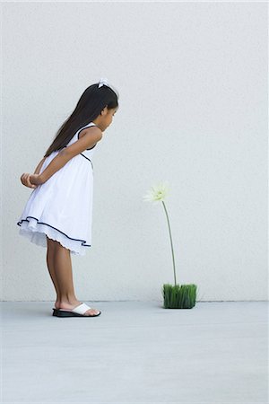 simsearch:632-01156895,k - Girl in sundress, leaning forward, looking at flower, side view Stock Photo - Premium Royalty-Free, Code: 696-03401943