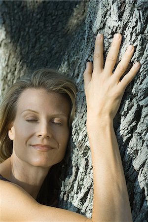 simsearch:633-01572737,k - Woman hugging tree, eyes closed, smiling, head and shoulders Foto de stock - Royalty Free Premium, Número: 696-03401958