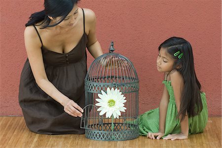 simsearch:695-03389506,k - Mother and daughter on floor on either side of birdcage containing flower, woman opening door of birdcage Foto de stock - Sin royalties Premium, Código: 696-03401953