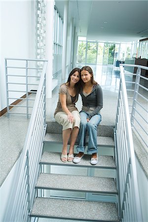 Mother and teenage girl together, sitting on steps, smiling at camera, full length Stock Photo - Premium Royalty-Free, Code: 696-03401982