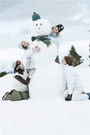snowman and child - Young female friends grouped around snowman Stock Photo - Premium Royalty-Free, Code: 696-03402006