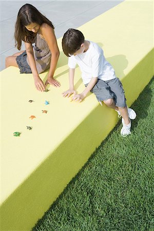 Mother and boy sitting outdoors, playing with plastic animal figurines, high angle view, full length Stock Photo - Premium Royalty-Free, Code: 696-03402031
