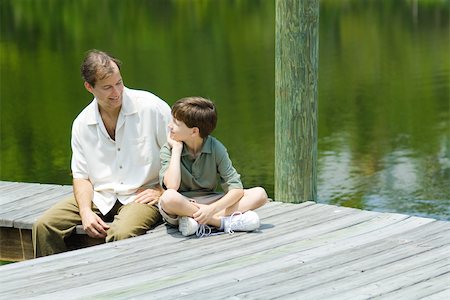 family hanging - Father and son sitting on dock, smiling at each other Stock Photo - Premium Royalty-Free, Code: 696-03402044