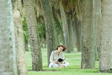 simsearch:614-06624865,k - Woman sitting in palm grove reading book Foto de stock - Sin royalties Premium, Código: 696-03402049