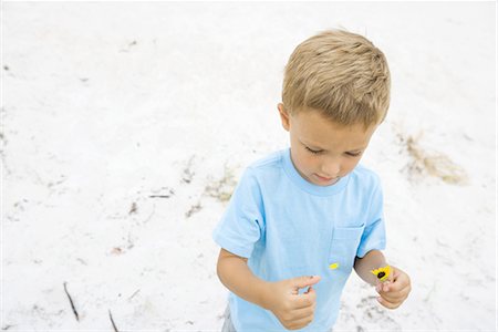 simsearch:695-03378542,k - Little boy picking petals from flower, high angle view, sand in background Foto de stock - Sin royalties Premium, Código: 696-03402042